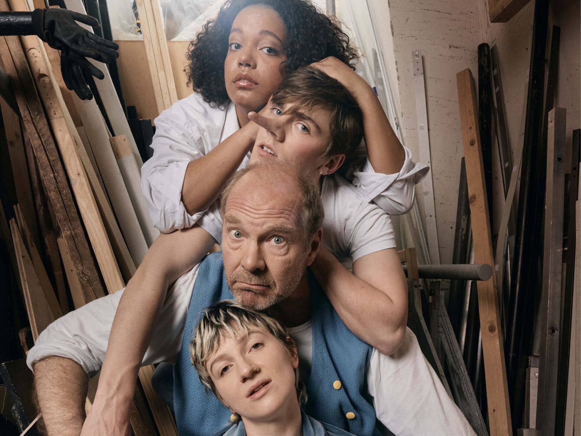 Ein Gruppe Menschen, die aufgereiht nach ben eineander umarmend sitzen, die dritte Figur hat eine lange Nase.