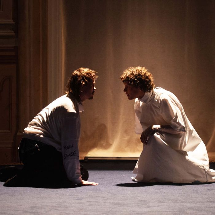 Zwei Personen knien am Boden und blicken einander in die Augen.