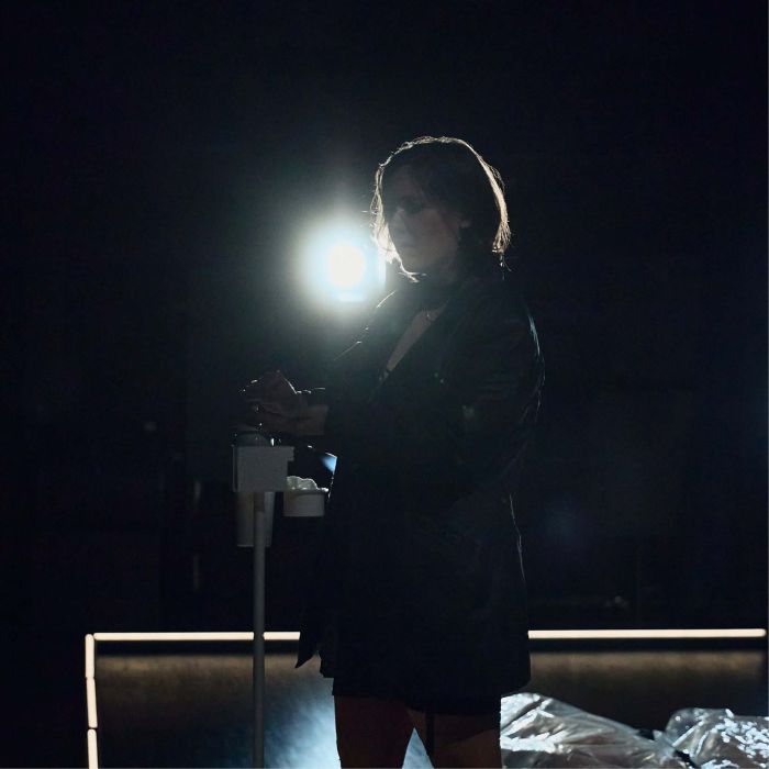 Eine Frauin schwarz gekleidet gegen das Scheinwerferlicht