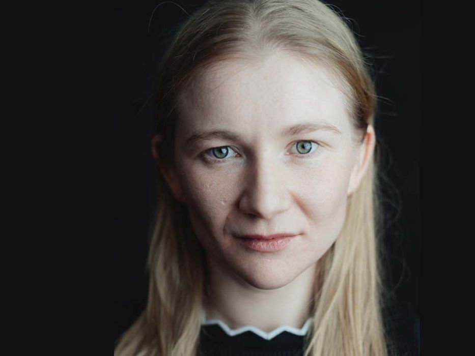 Portrait einer Frau mit blonden Haaren vor schwarzen Hintergurn