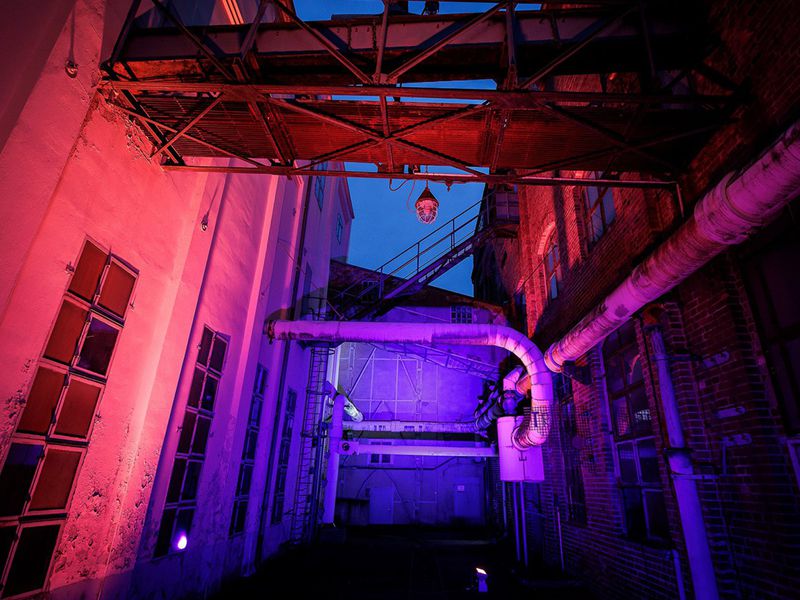 Eine alte Farbik in blau-rosa Gegenlicht bei Nacht.