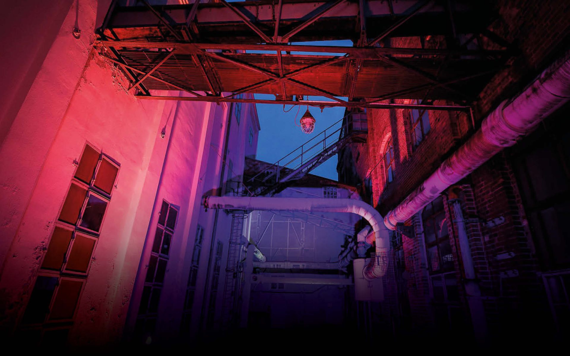 Eine alte Farbik in blau-rosa Gegenlicht bei Nacht.