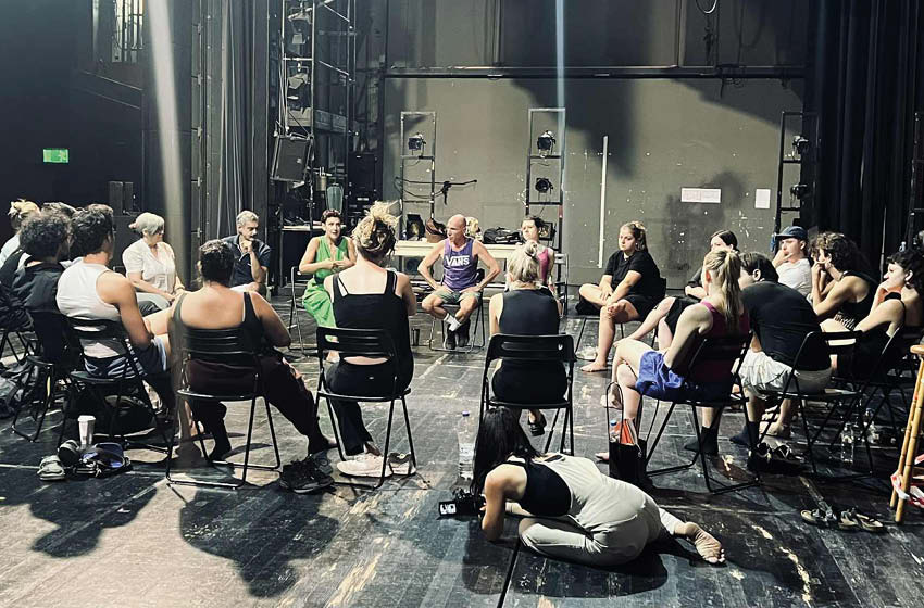 Eine Gruppe, die im Sesselkreis sitzt und einer Person zuhört.